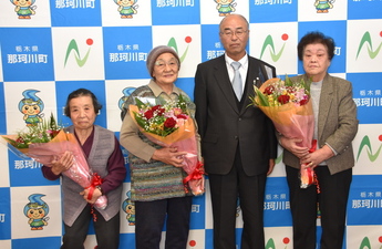 花束を持った3人の高齢の女性と町長の写真