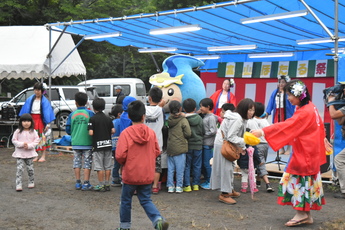 ゆるキャラの周りを囲む子どもたちの写真