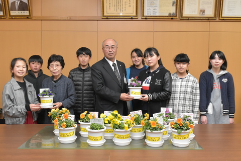パンジーの鉢植えを前にした小学生と町長の記念写真
