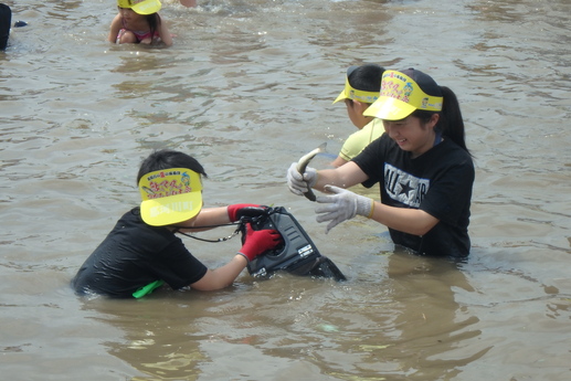 男の子が持つびくに、捕まえた鮎を入れる女の子の写真