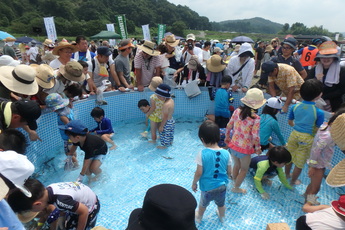 子ども専用プールで小さなお子さんたちが魚を捕まえている写真