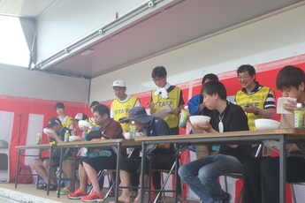 ステージ上で、うな丼を早食いしている男性6人の写真