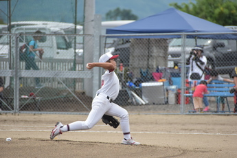 投手が腕をしならせ、ボールを投げる横姿の写真