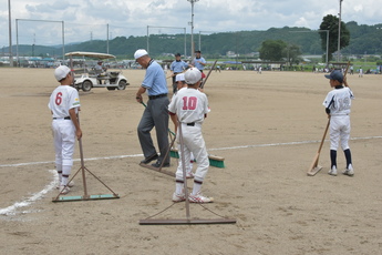 試合終了後、グラウンド整備する両チーム選手と審判員の写真