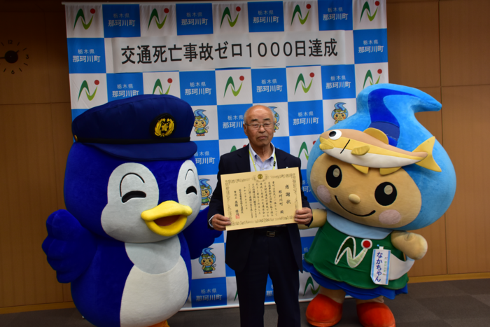 栃木県警察本部から贈られた感謝状を持つ町長の両脇にゆるキャラたちがいる写真 栃木県警察本部から贈られた感謝状を持つ町長の両脇にゆるキャラたちがいる写真