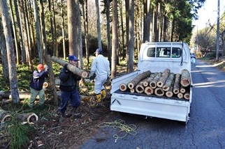 木材を担いで運ぶ男性の写真