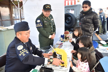缶バッジを作る子どもと自衛官の写真