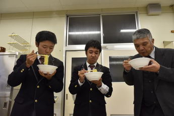 ラーメンを試食している生徒と先生の写真