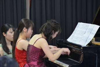 ピアノの連弾をしている二人の女性の写真 ピアノの連弾をしている二人の女性の写真