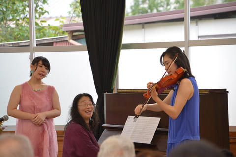 ヴァイオリンを演奏する女性と歌う2人の女性の写真