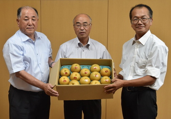 梨が入った箱を持った3人の男性の写真