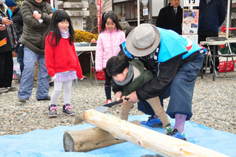丸太切り体験をする子どもの写真