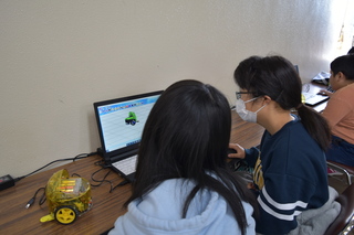 パソコンを使ってプログラミングを編集する生徒の写真