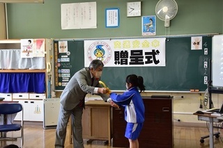 男性から傘を受け取る女子児童の写真