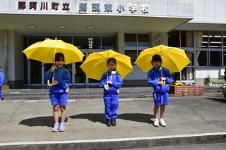傘をさす3人の児童の写真