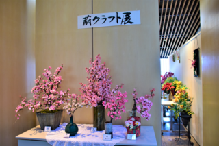 繭玉で作られた木に咲く桃色の花の写真