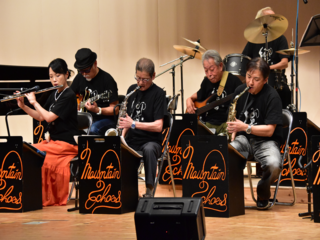 サックス、フルート、ギター、ベース、ドラムの演奏中の写真