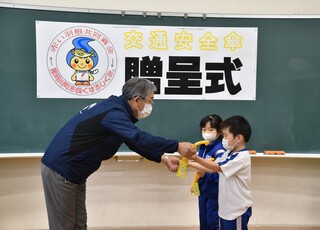 2名の代表児童が社会福祉協議会の会長から傘を受け取っている写真