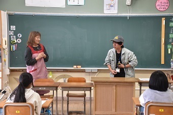 エプロンを着た女性とキャップを被った男性が寸劇をしている写真