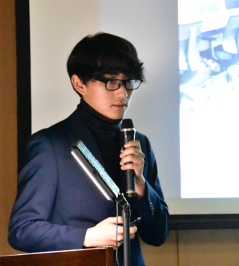 マイクを持って発表する地域おこし協力隊隊員の写真 マイクを持って発表する地域おこし協力隊隊員の写真