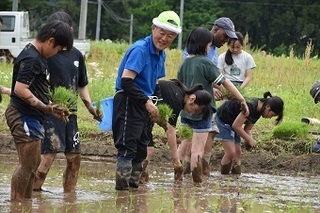 田植えをする小学生と地元農家の写真