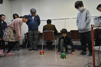 プログラミング教室で、生徒がプログラミングを入力したロボットを走らせている様子