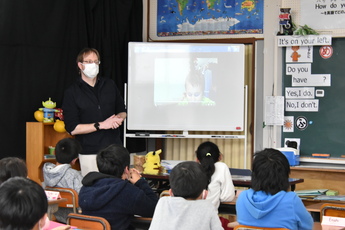 教室のスクリーンに映ったホースヘッズ村の小学３年生の話しを聞き取る小川小３年生の児童たち