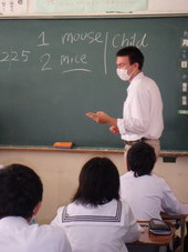 黒板に英語を書きながら、生徒たちに教えている、ジェイクさん